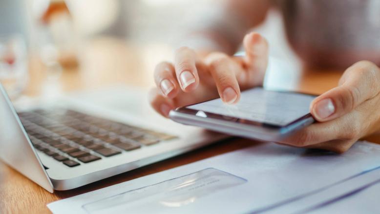 A person using their mobile phone and laptop