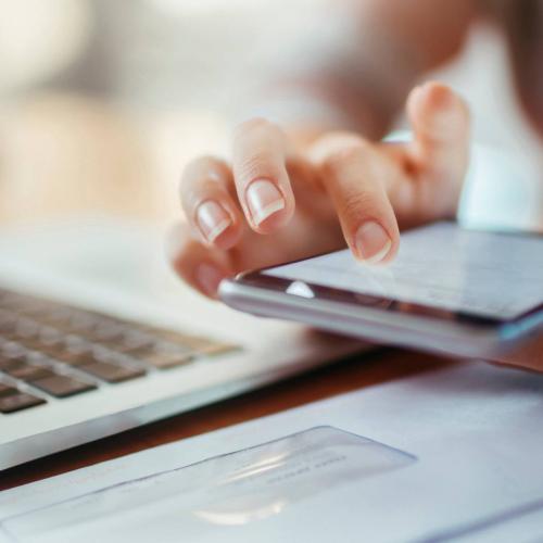 A person using their mobile phone and laptop